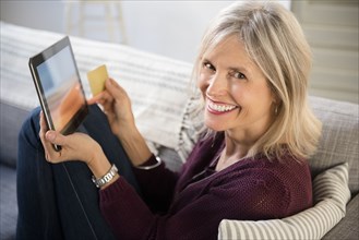 Smiling Caucasian woman online shopping with digital tablet