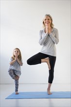 Caucasian granddaughter imitating grandmother practicing yoga