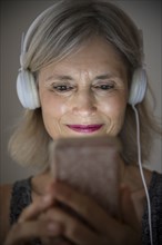 Smiling Caucasian woman listening to music on cell phone