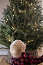 Caucasian baby boy looking up at Christmas tree