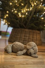 Teddy bear laying on floor near Christmas tree