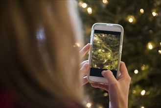 Caucasian woman photographing Christmas tree with cell phone