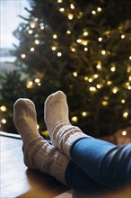 Socks of Caucasian woman with feet on table near Christmas tree