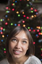 Pensive Mixed Race woman near Christmas tree