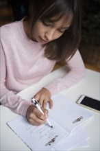 Mixed Race woman writing list in notepad