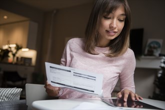 Mixed Race woman paying bills on digital tablet