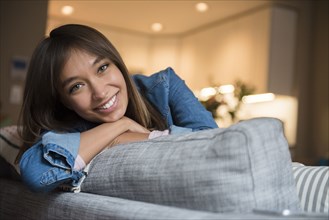 Smiling Mixed Race woman leaning on sofa