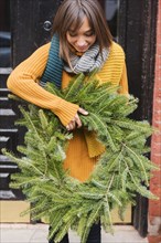 Mixed Race woman carrying pine wreath outdoors