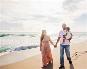 Couple walking on beach with baby daughter