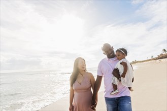 Couple walking on beach with baby daughter