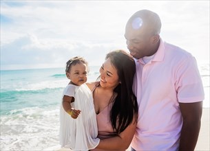 Couple admiring baby daughter on beach