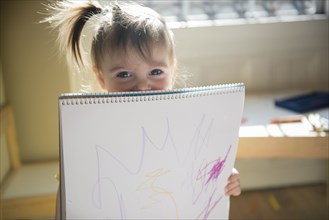 Caucasian baby girl showing drawing on sketchpad