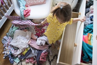 Caucasian baby girl removing clothing from dresser drawer