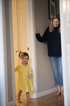 Mother watching Caucasian baby daughter standing in doorway
