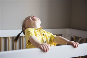Caucasian baby girl laughing in crib