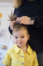 Caucasian mother styling hair of baby daughter