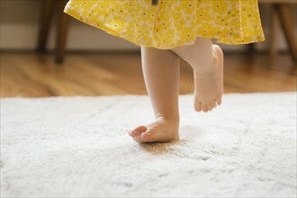 Barefoot Caucasian baby girl walking on rug