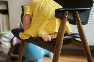 Barefoot Caucasian baby girl laying on chair