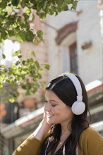 Caucasian woman listening to headphones in city
