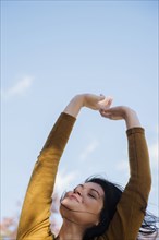 Wind blowing hair of Caucasian woman with arms raised