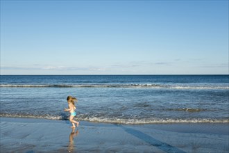 Caucasian girl running on beach