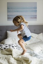 Caucasian girl jumping on bed