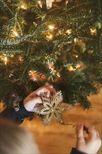 Caucasian girl hanging star ornament on Christmas tree