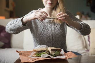 Woman photographing sandwich with cell phone