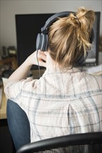Woman using computer and listening to headphones