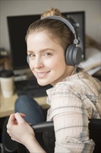Portrait of smiling woman using computer and listening to headphones