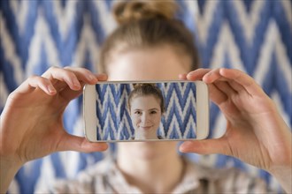 Woman holding photograph of cell phone selfie in front of face