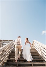Caucasian bride and groom climbing wooden staircase