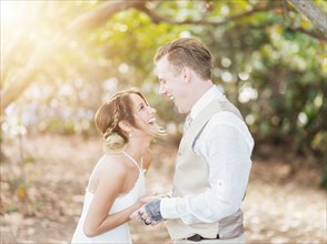Caucasian bride and groom laughing outdoors