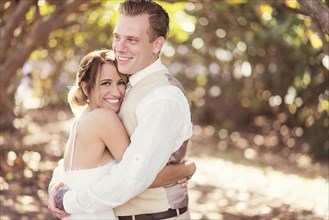 Caucasian bride and groom hugging outdoors