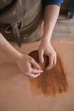Hands of Caucasian woman rolling pottery clay