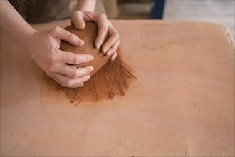 Hands of Caucasian woman rolling pottery clay