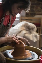 Caucasian woman shaping pottery clay on wheel