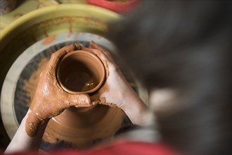 Caucasian woman shaping pottery clay on wheel