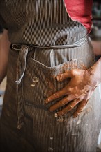 Caucasian woman wiping hands covered with pottery clay on apron