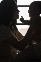 Silhouette of Caucasian mother holding baby son