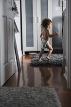 Caucasian boy wearing diaper running in corridor