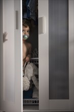 Caucasian boy hiding in closet peeking from doorway