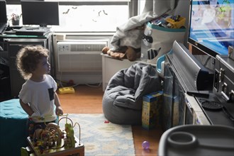 Caucasian boy playing in livingroom with toys and watching television