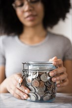 Smiling African American woman with jar full of coins