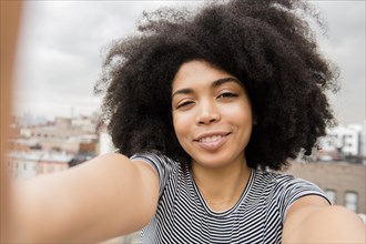 Smiling African American woman posing for selfie on rooftop