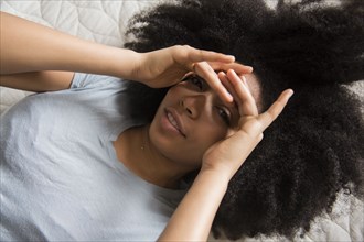 African American woman laying in bed shielding eyes