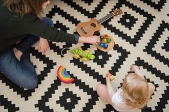 Caucasian mother and daughter sitting on floor playing with toys