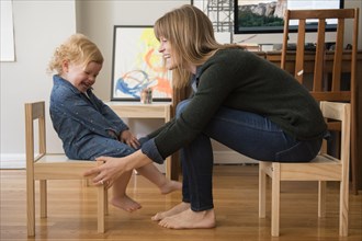 Caucasian mother and daughter sitting on small chairs in home office