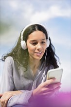 Hispanic woman listening to cell phone with headphones
