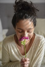 Hispanic woman smelling flower